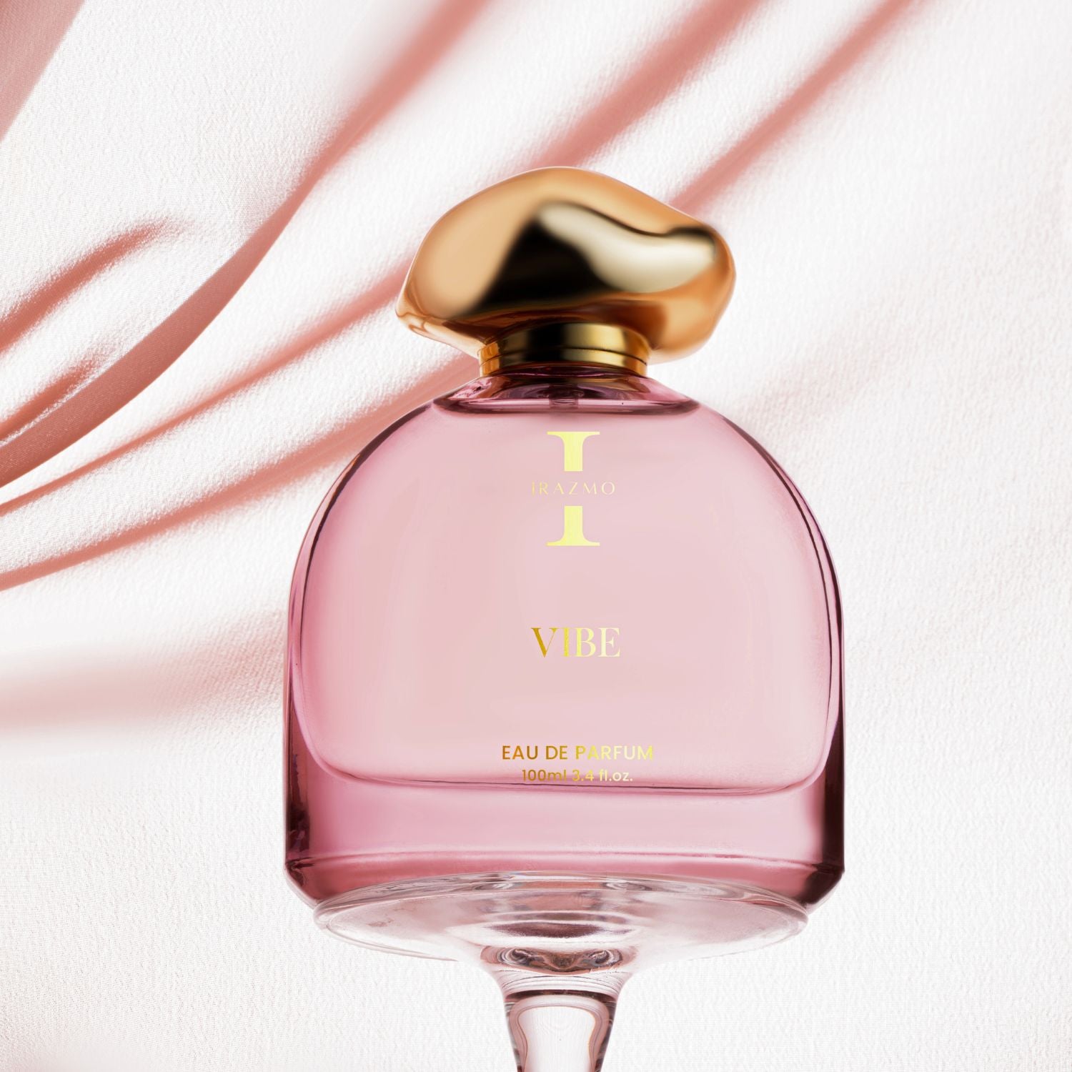 Pink perfume bottle with gold cap on a soft pink background