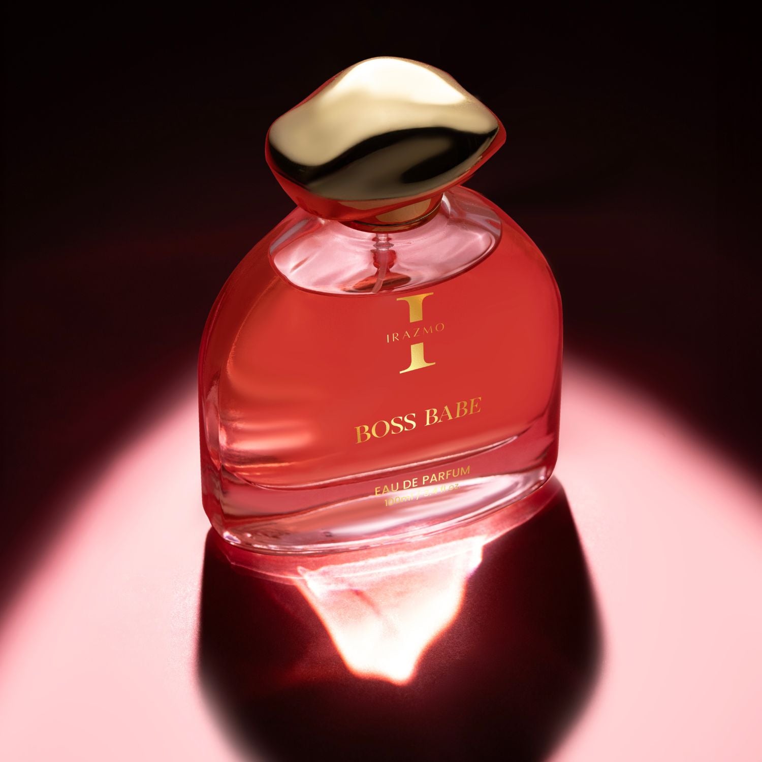 Red perfume bottle with gold cap on a reflective surface