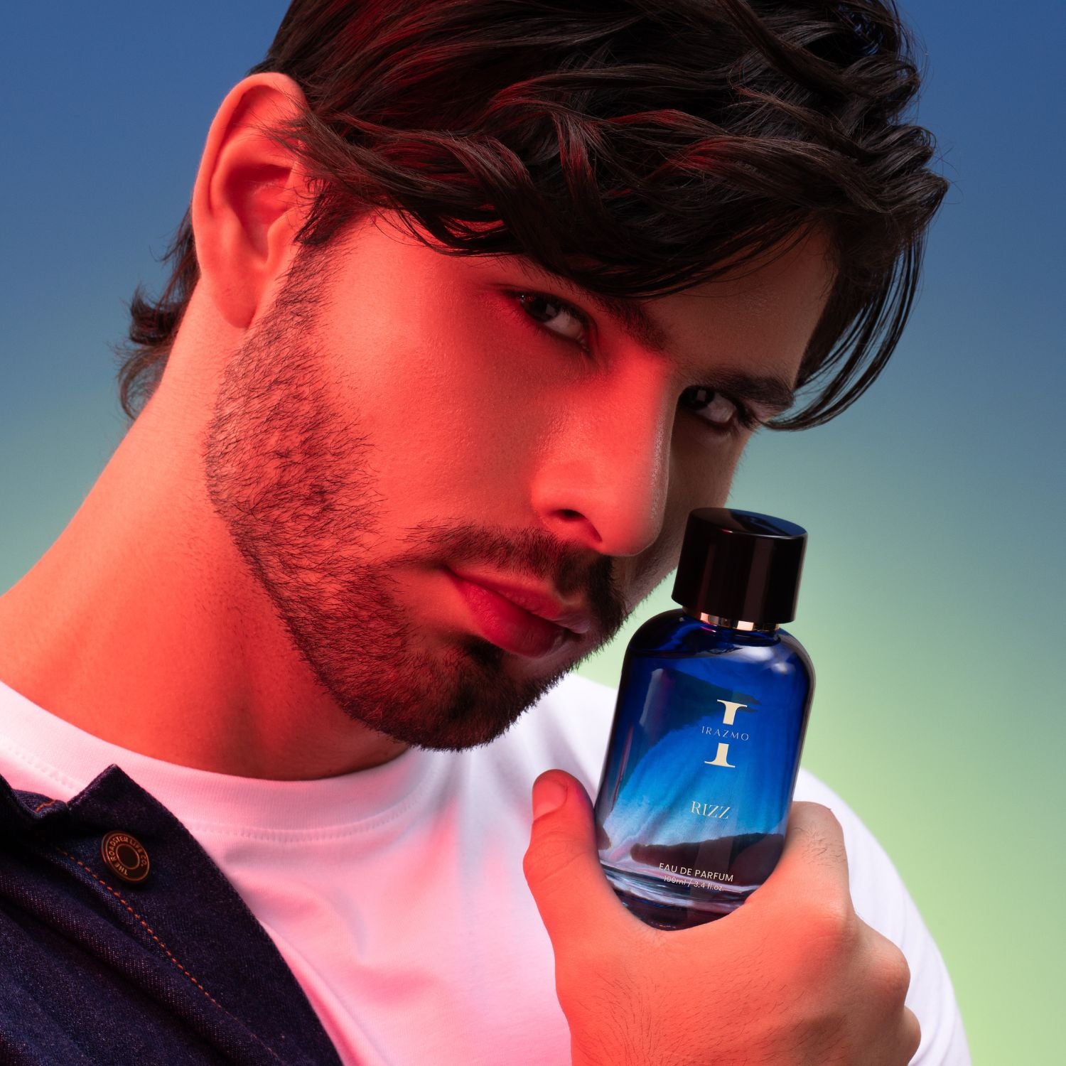 Man holding a blue perfume bottle with a gradient background
