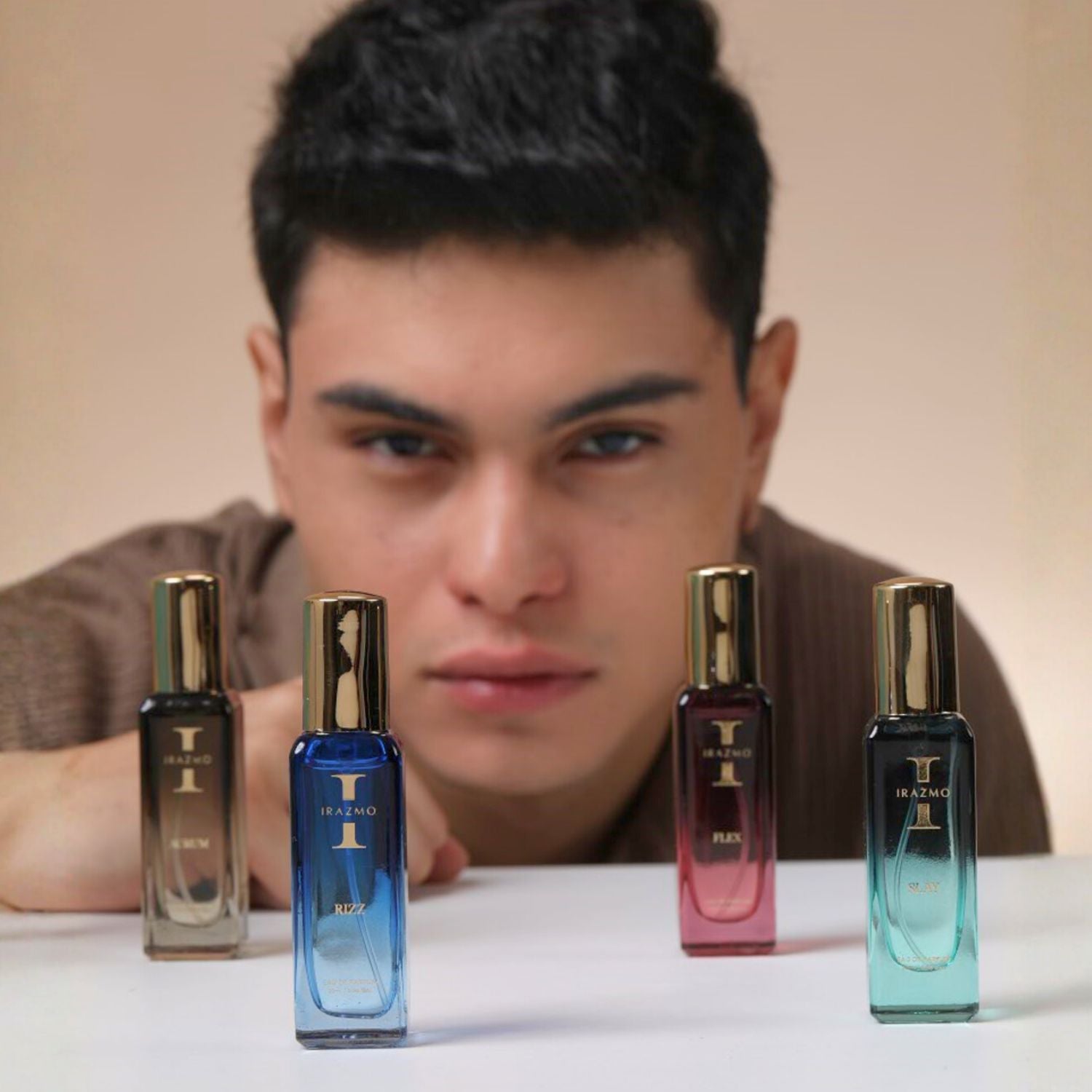 Man sitting behind four perfume bottles on a table