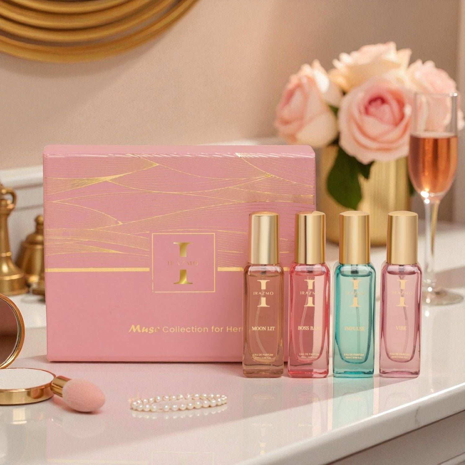 Set of perfume bottles with a pink packaging box on a decorative surface with flowers and a glass.
