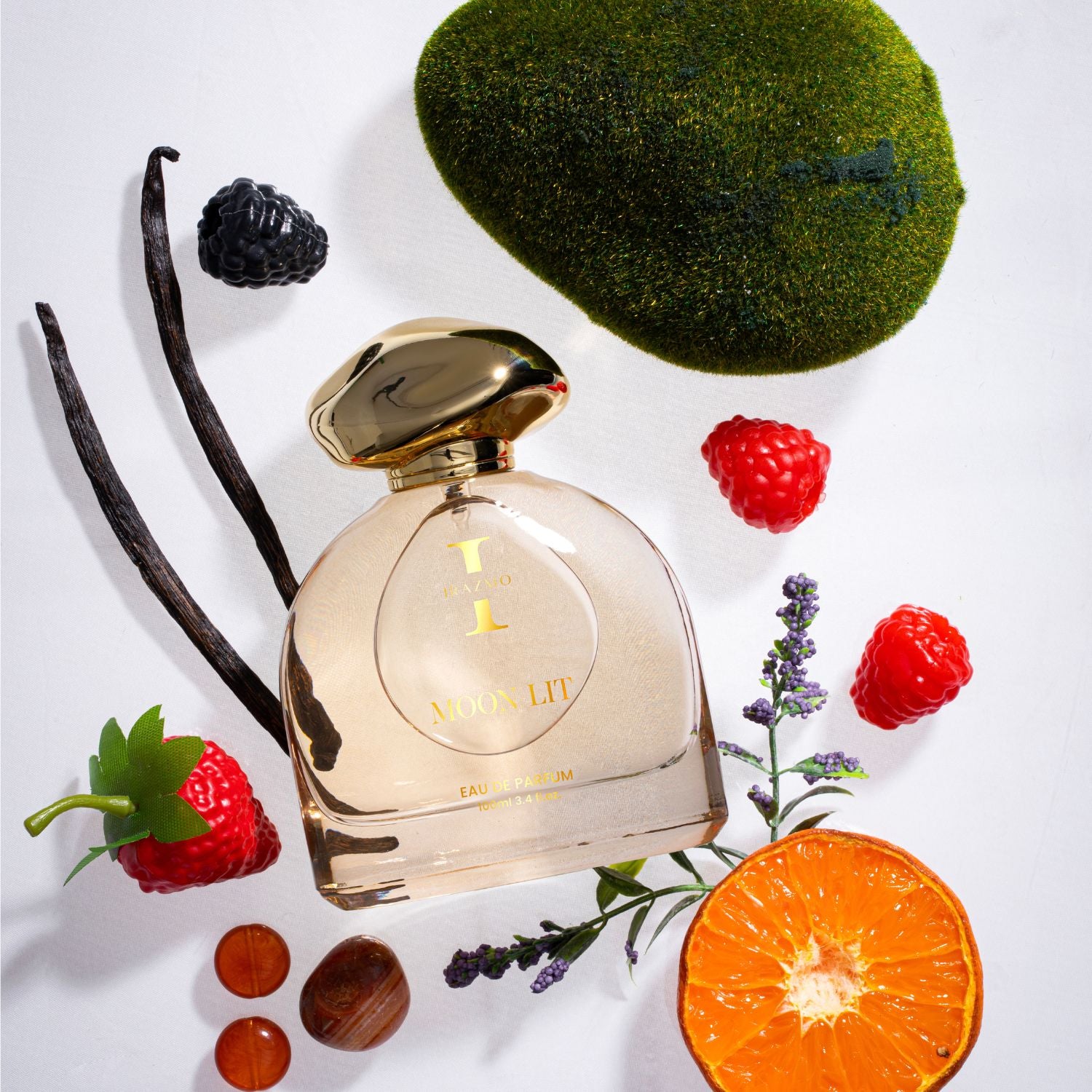 Perfume bottle with vanilla bean, blackberry, orange, and other elements on a white background