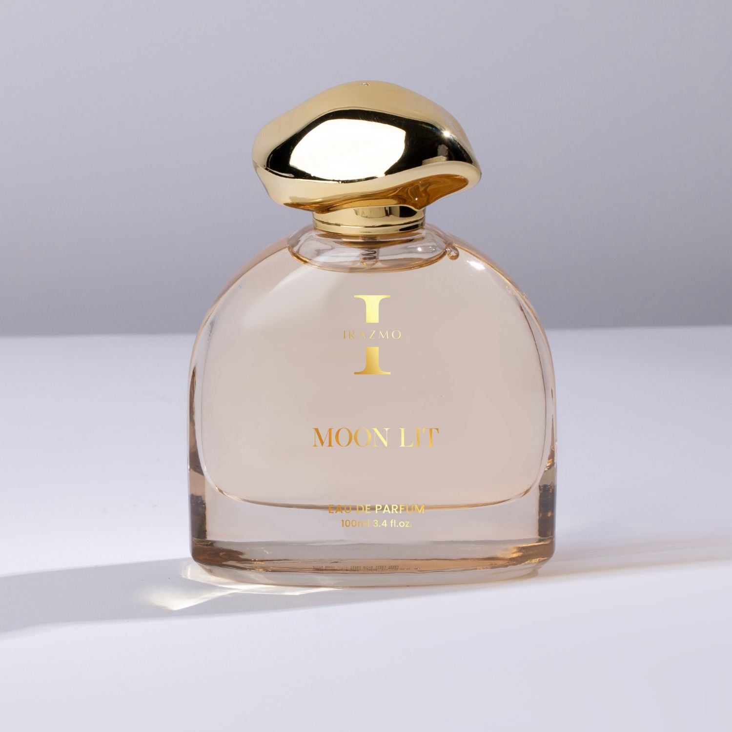 Perfume bottle with gold cap and 'MOON LIT' branding on a light background