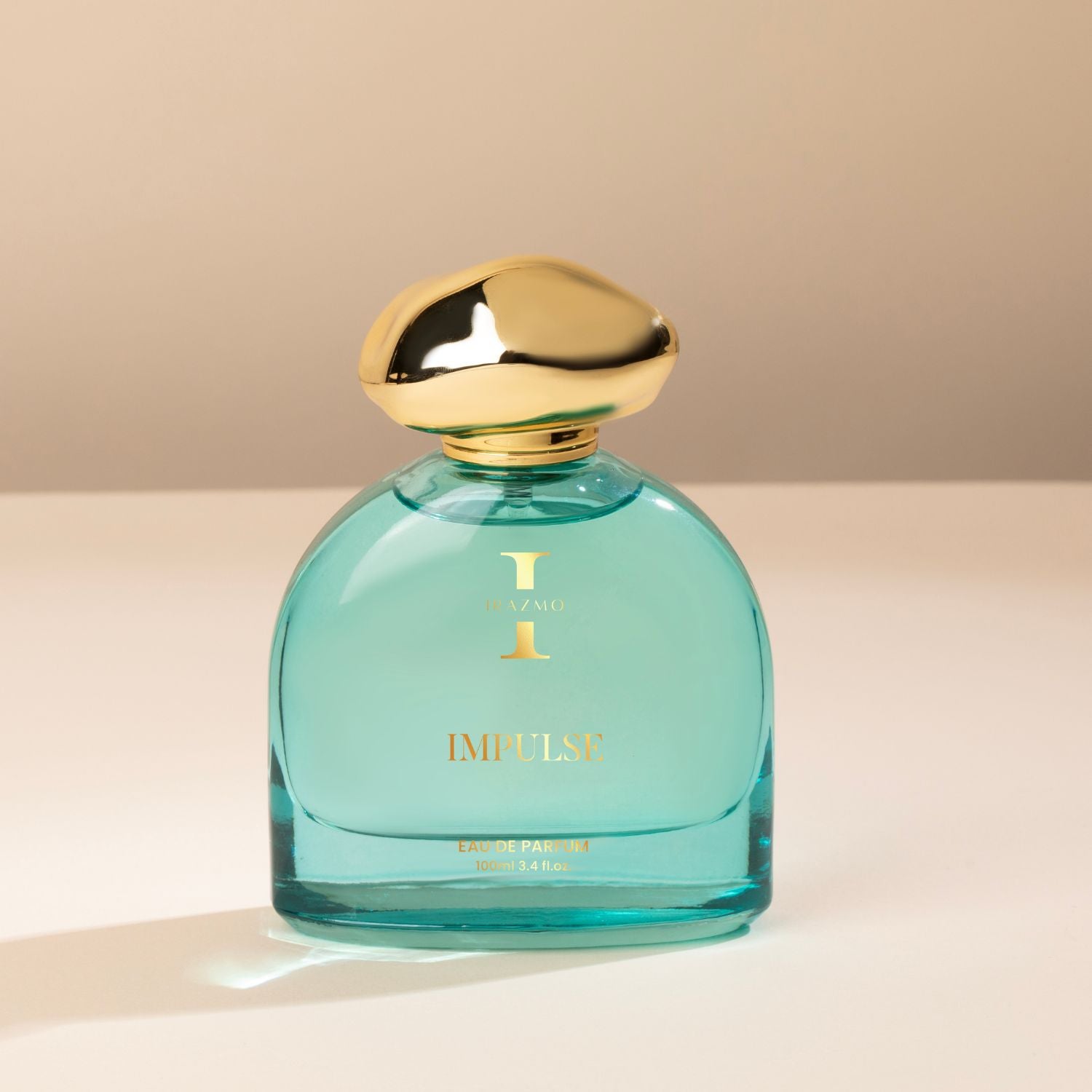 Teal perfume bottle with gold cap on a beige background