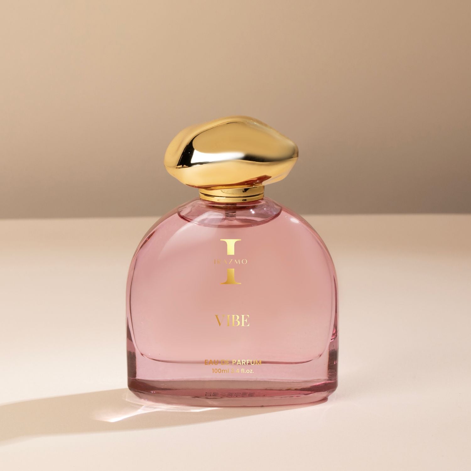 Pink perfume bottle with gold cap on a beige background