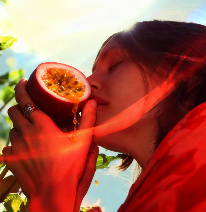 Person eating a halved passion fruit with a blurred natural background