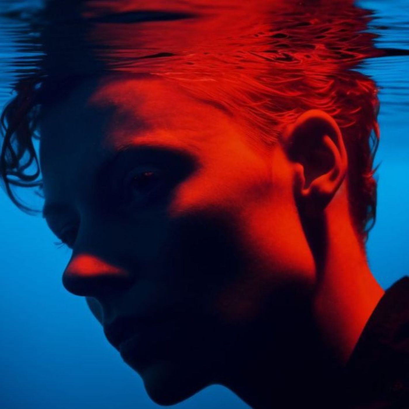 Underwater silhouette of a person with red hair and blue water.