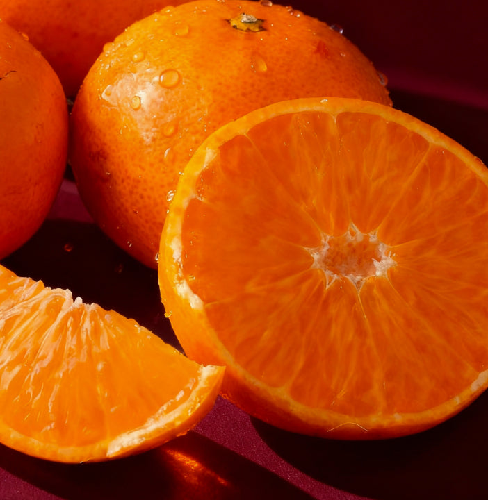 Oranges with a close-up of a halved orange on a red background