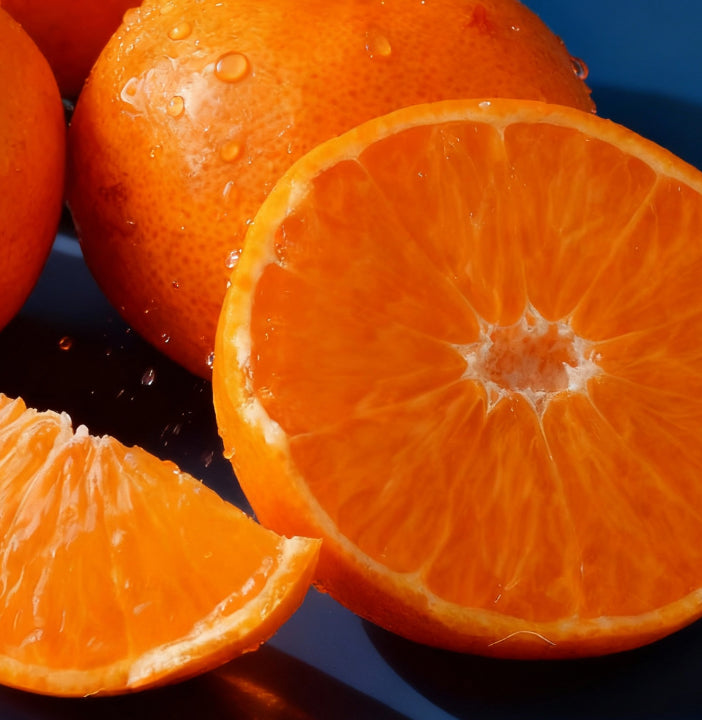Oranges with one sliced open on a dark background