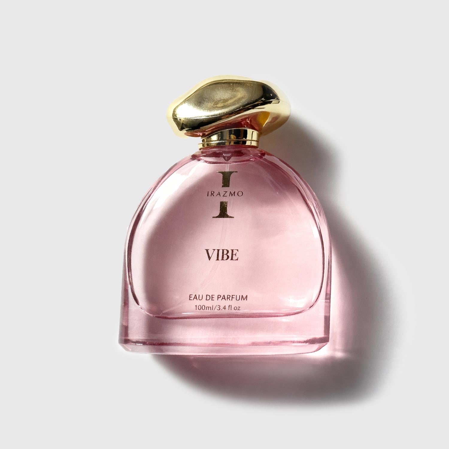 Pink perfume bottle with gold cap on a light gray background