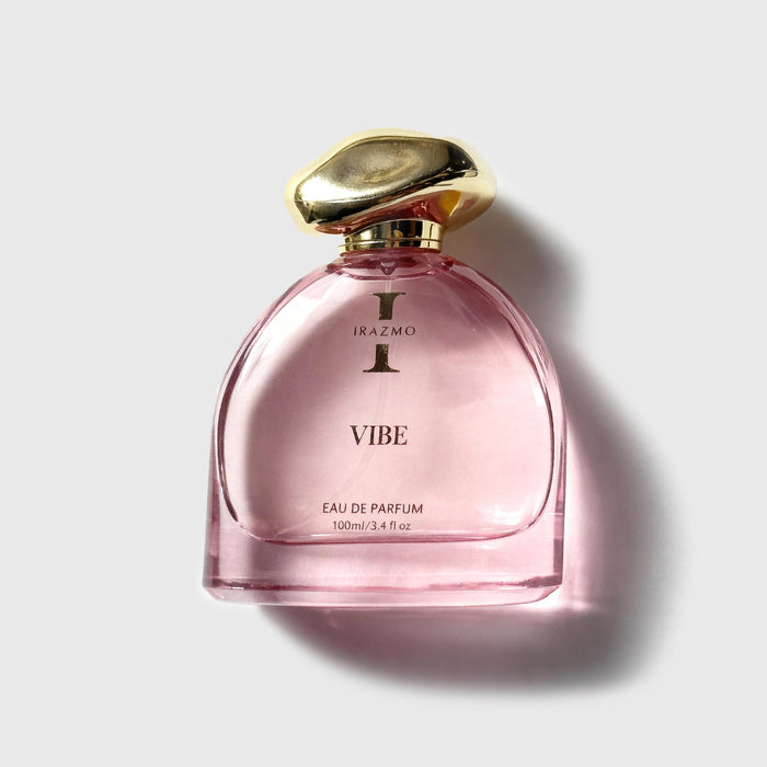 Pink perfume bottle with gold cap on a light gray background