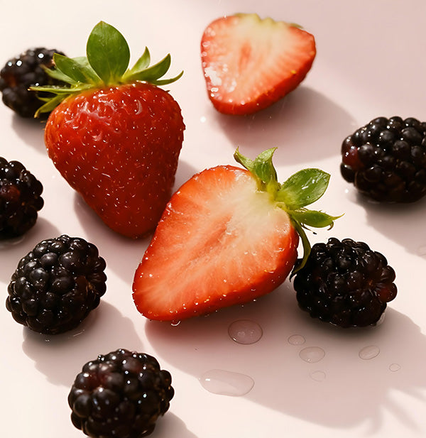 Strawberries and blackberries on a white surface
