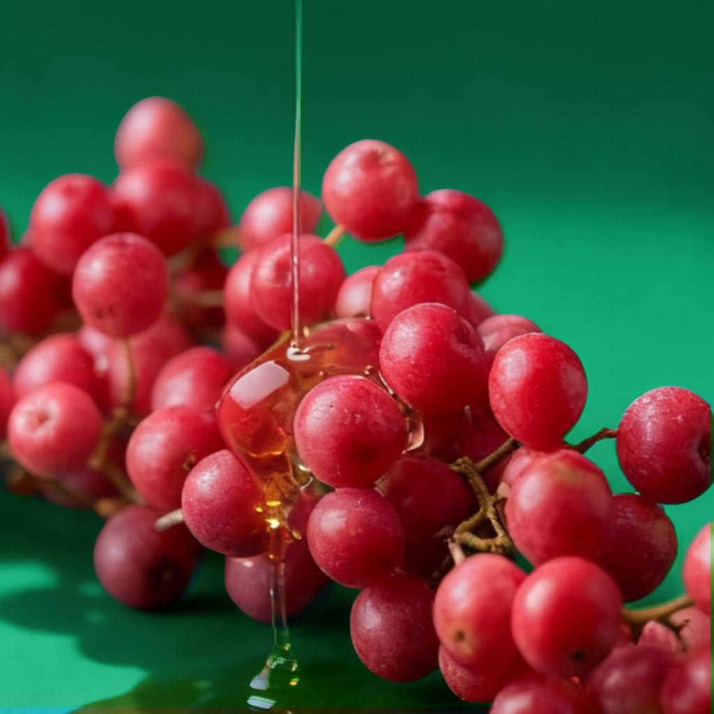 Red berries with honey drizzling over them against a green background