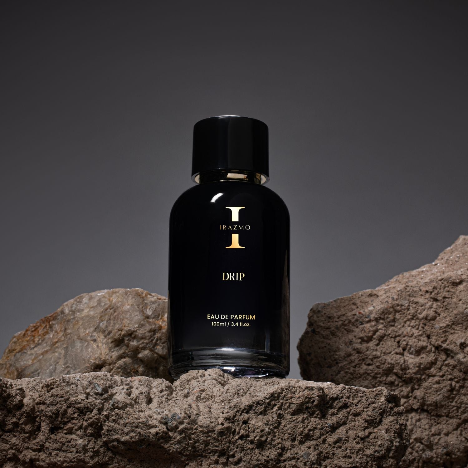 Black perfume bottle with gold text on a rock surface
