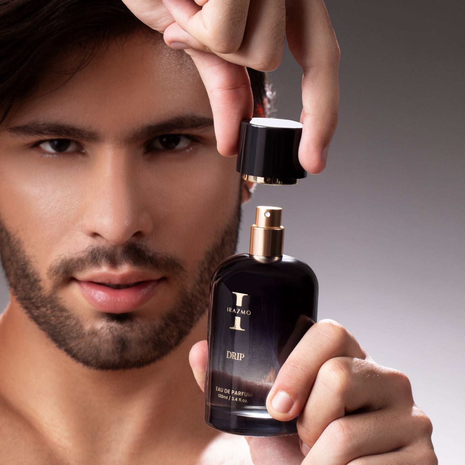 Man holding a black perfume bottle labeled 'Drip' with a blurred background