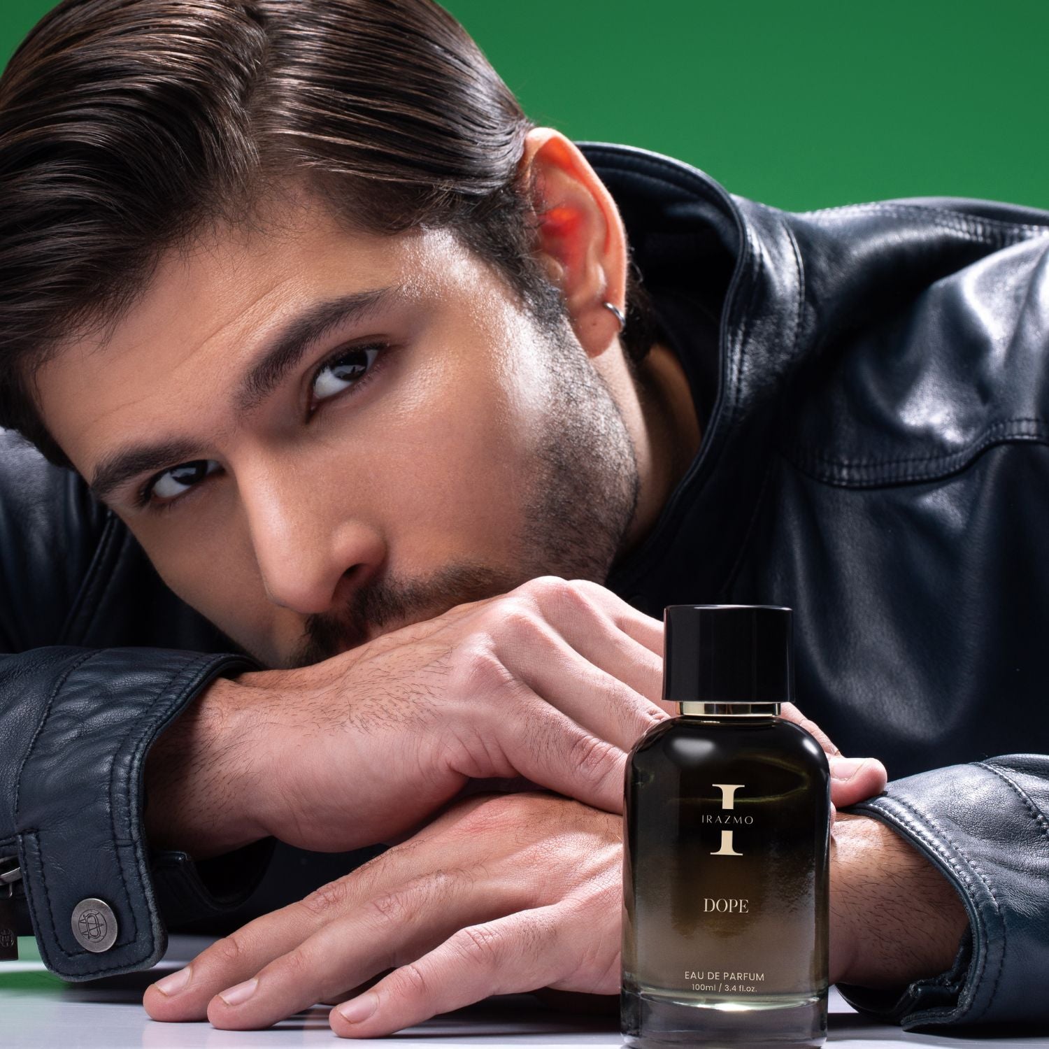 Man leaning on a table with a DOPE perfume bottle in front of him against a green background