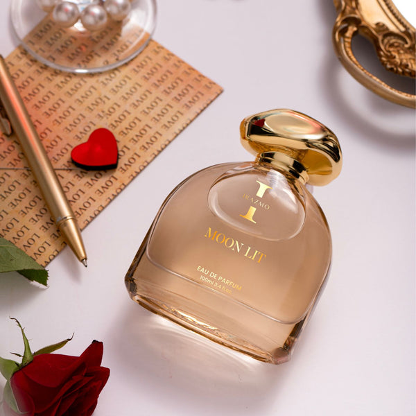 Perfume bottle labeled 'Moon Lit' with a red rose and decorative items on a light background