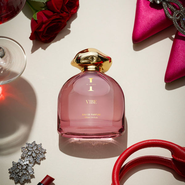 Pink perfume bottle with gold cap on a light surface with decorative items around