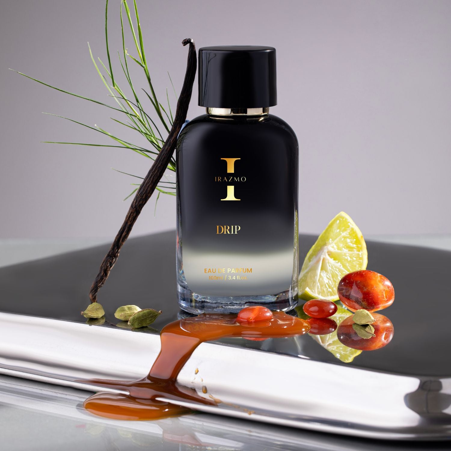 Black perfume bottle labeled 'I' with vanilla bean, lime, and red berries on a reflective surface.