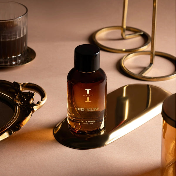 Perfume bottle labeled 'Oudh Eclipse' on a reflective surface with gold decor