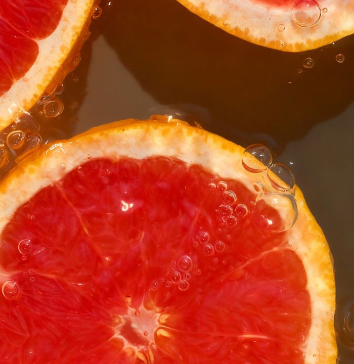 Close-up of sliced grapefruit with water droplets on a dark background